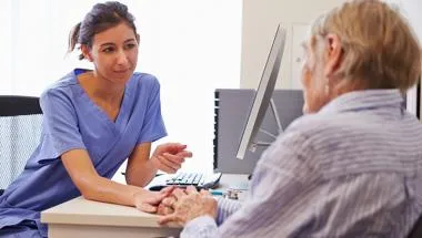 Female doctor giving advice to elderly person at a desk 780