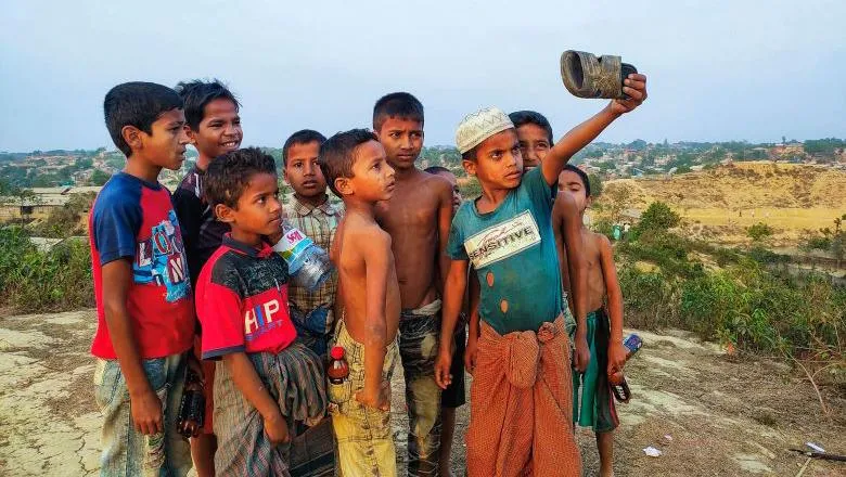 A group of children take a selfie using a sandal on a hilltop in Balukhali camp. 