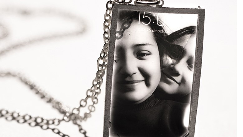 A photograph of two women on a SIM card on a necklace chain