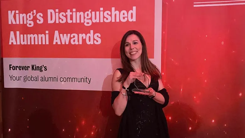 Andreia Trigo holding trophy in front of red background