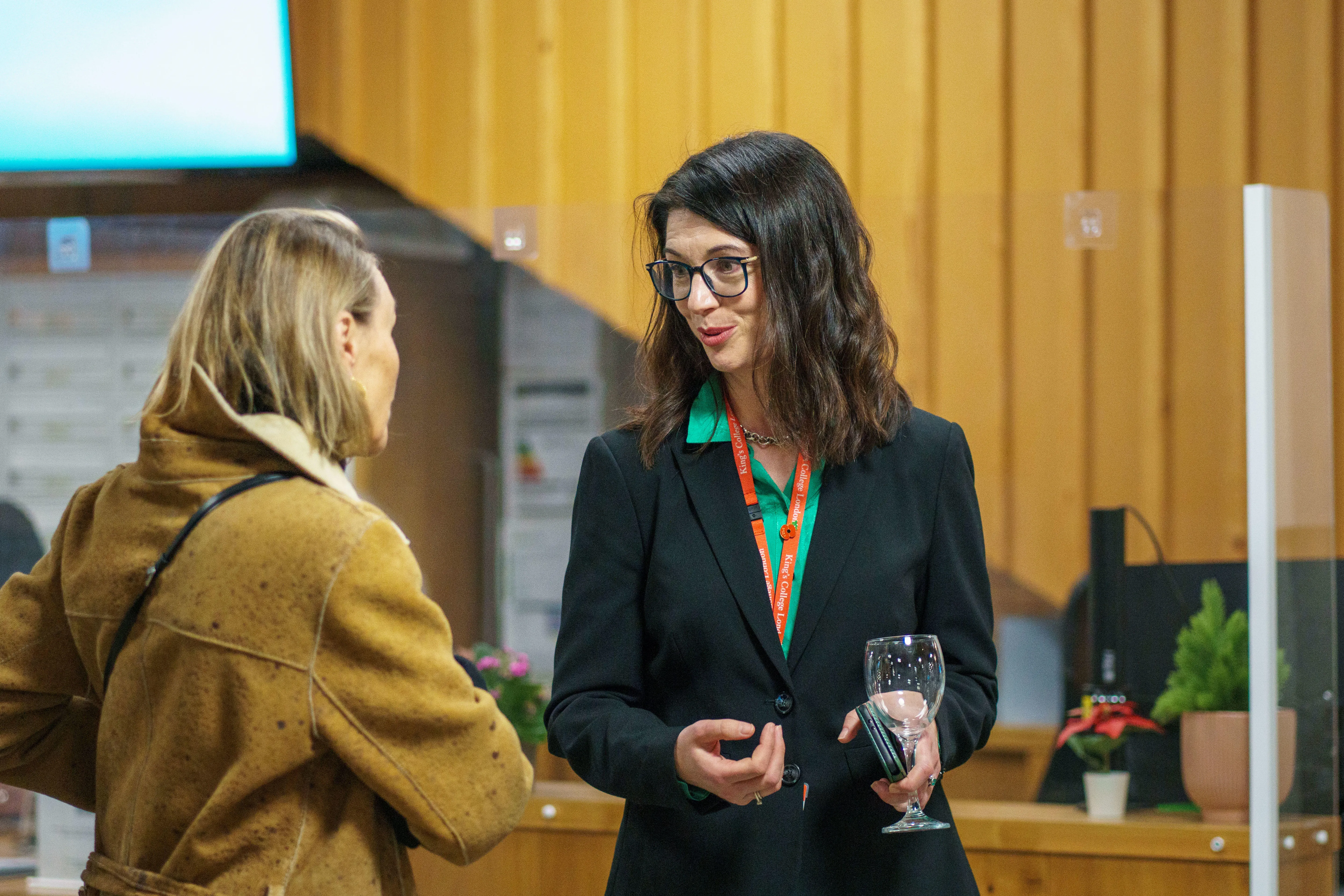 A woman engages in conversation with another woman at an art exhibition