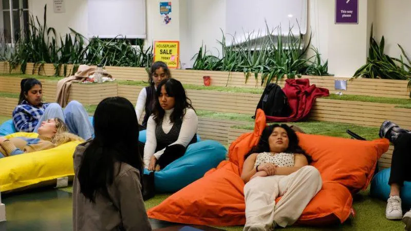 A group of young people seated and reclining on colorful bean bags in an indoor lounge area, some with closed eyes and appearing relaxed.