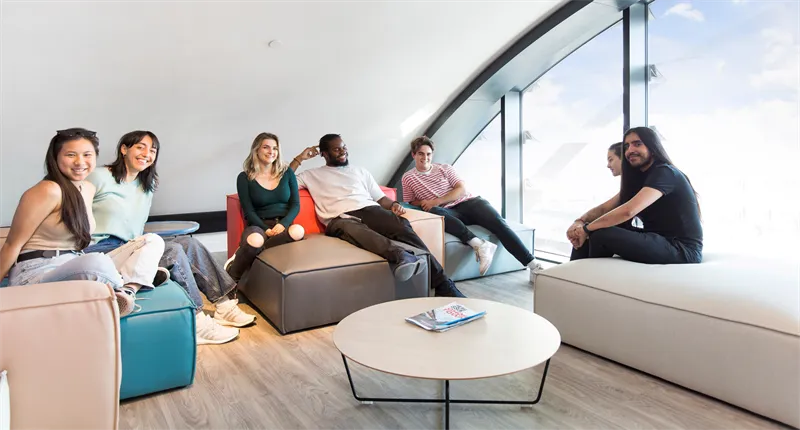 Seven students sat in a bright common room smiling at the camera