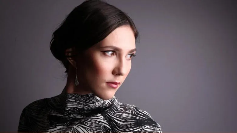 Portrait of Lara Poe in front of a grey background.