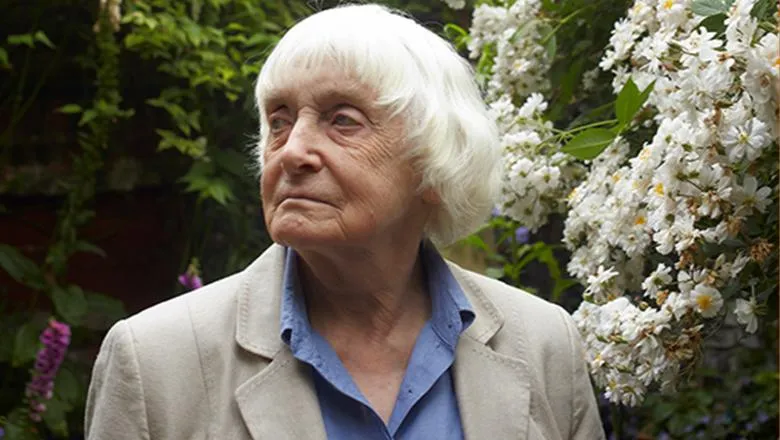 Maureen Duffy in front of a flowering white plant.