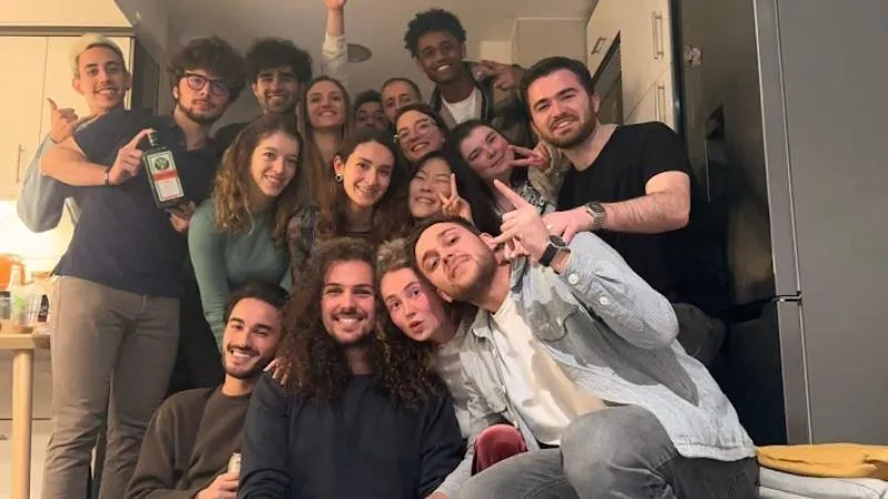 Alex and friends smiling and posing together in a cozy kitchen, enjoying their time together.