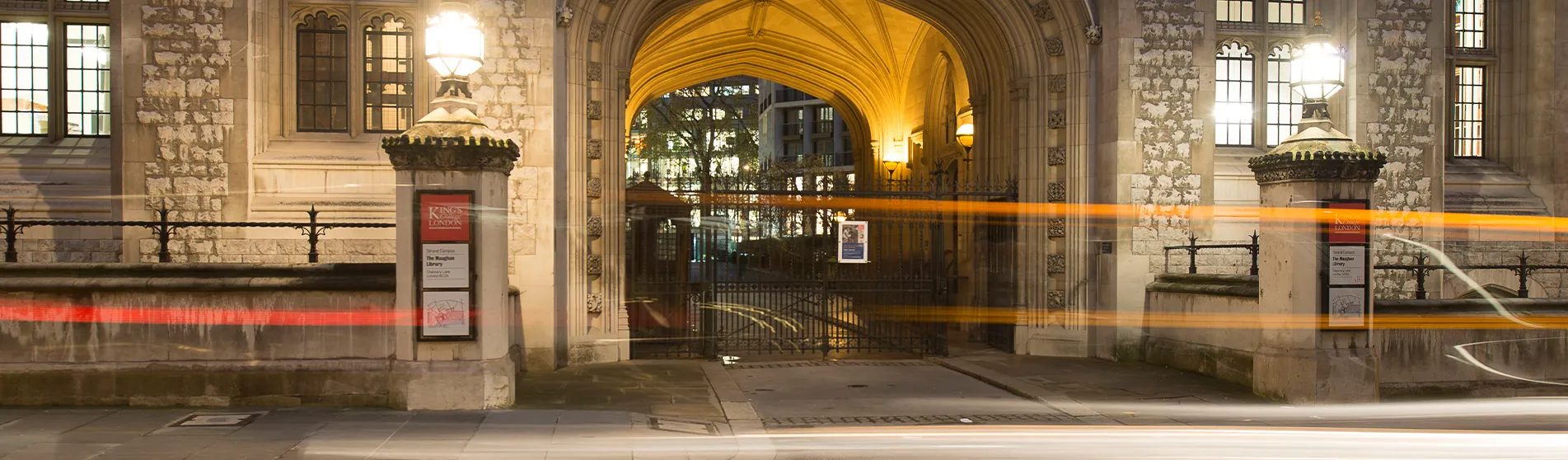Two streetlights shine outside the front entrance to the Maughan Library at night