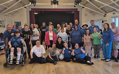 A large group of people posing for a photograph in a rehearsal studio