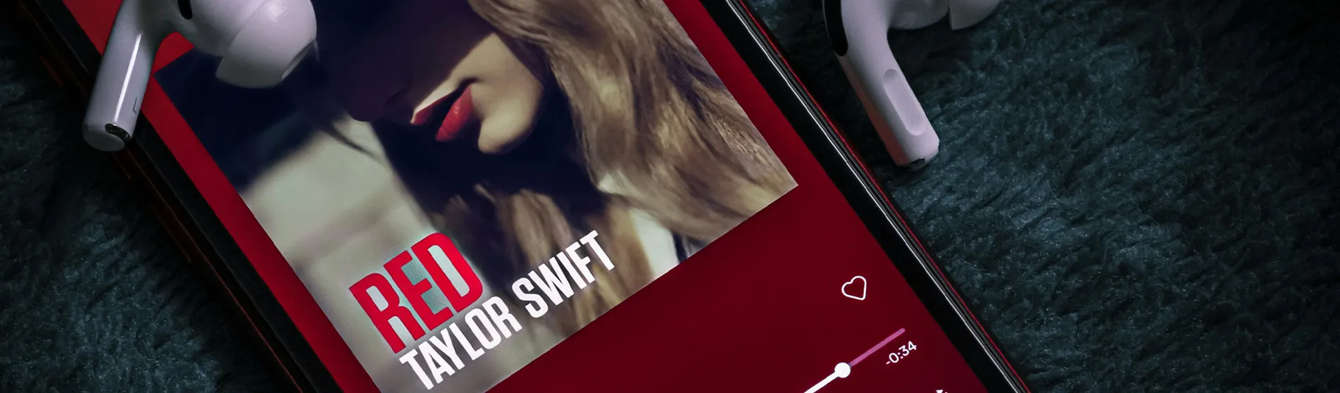 An image of a phone playing Taylor Swift's 'Red' album, accompanied by two white airpods