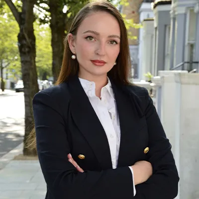 A young woman in a relaxed business suit with her arms folded looks into the camera