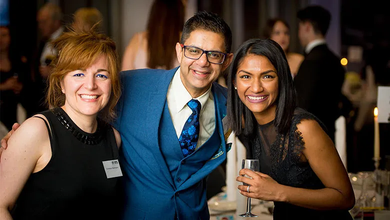 Alumni pose for a group photo at a networking event