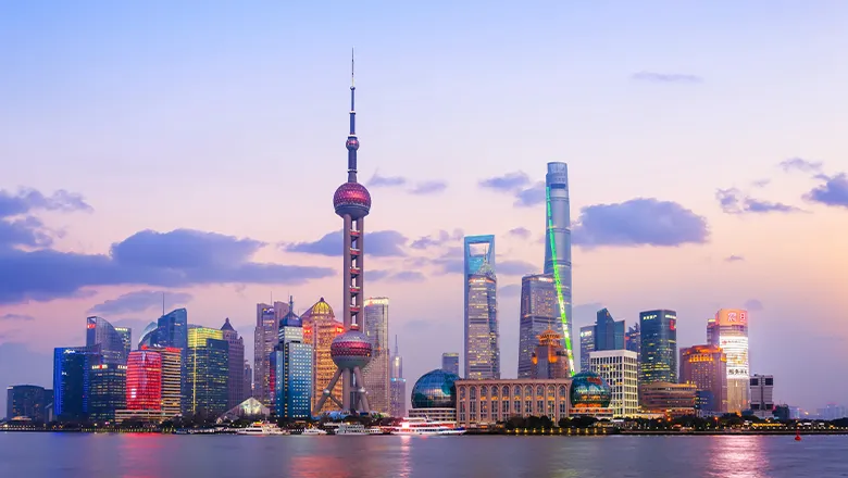 A waterside cityscape of tall skyscrapers set against dusk sky.