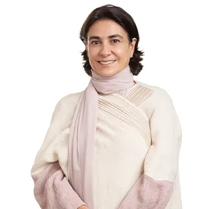 A woman with brown hair wears a light pink scarf and white top.