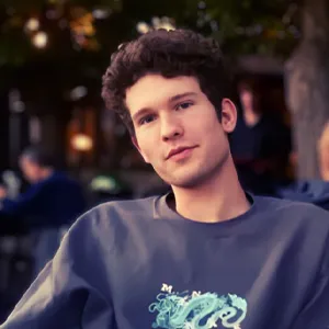 A man with short, dark hair wearing a blue top.