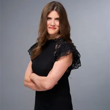 A young woman with long hair and a stylish black dress smiles as she poses for the camera