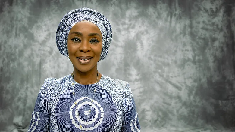 A woman wearing a patterned outfit smiles warmly