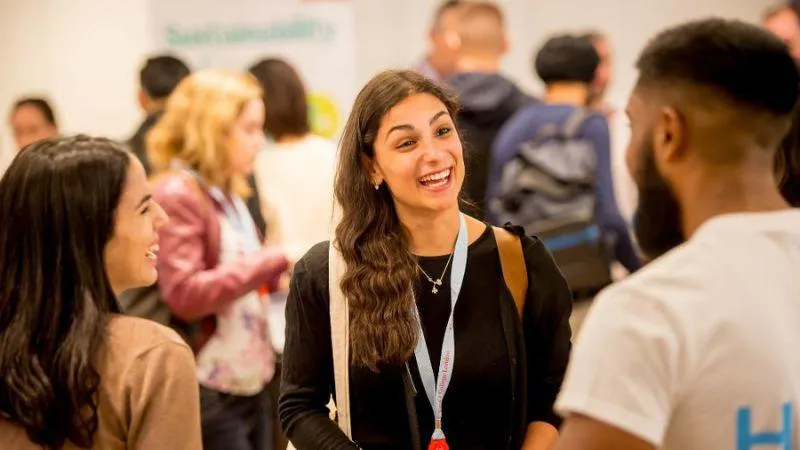 A group of students and young professionals engaged in a lively conversation at an event.