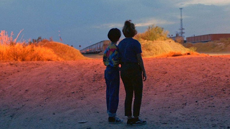 Two people stood next to each other in the desert looking in the sunset