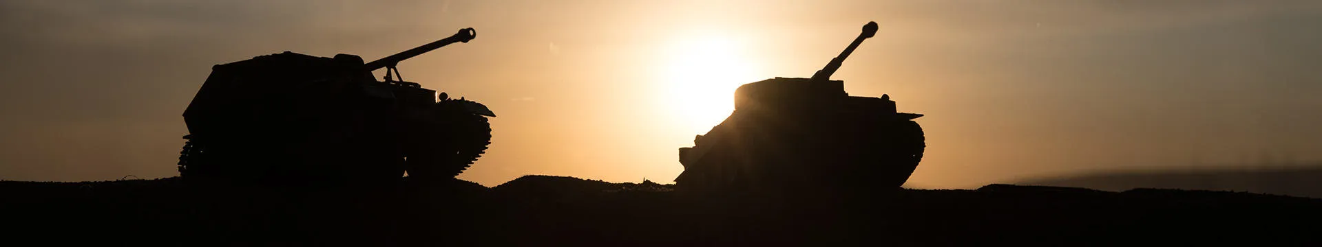 Two shaded army tanks, with the setting sun in the background.