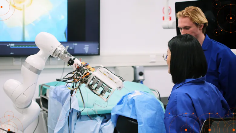 Man and woman standing near KUKA robot arm