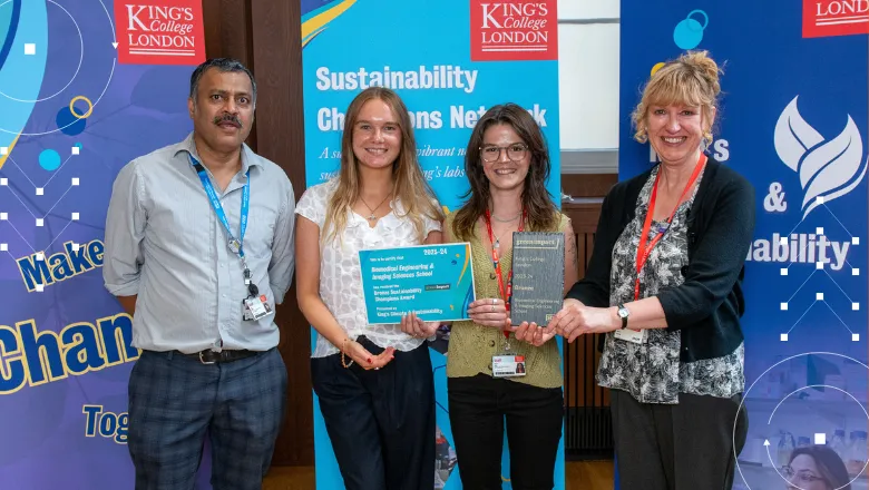 four people stand with awards in hand in front of banners