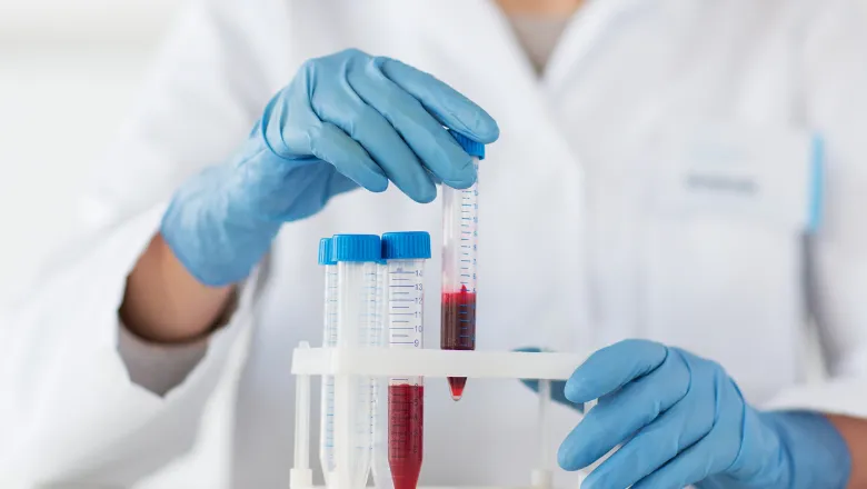 Scientist wearing blue gloves handling test tubes in the laboratory.