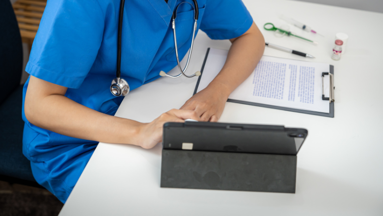 Trainee doctor sitting at a desk using a digital tablet.