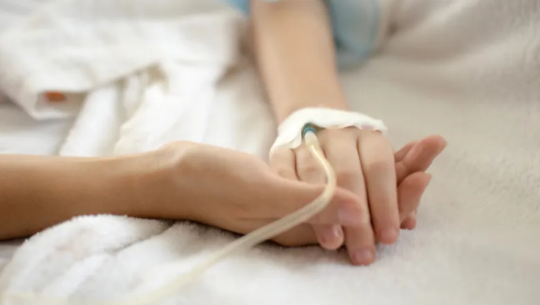 Adult holding a child's hand in hospital.