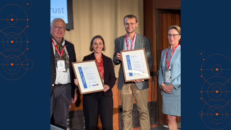 Two people with framed certificates standing in the middle of two people.
