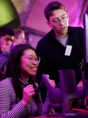 A researcher guiding a young participant through a VR surgical game at the event