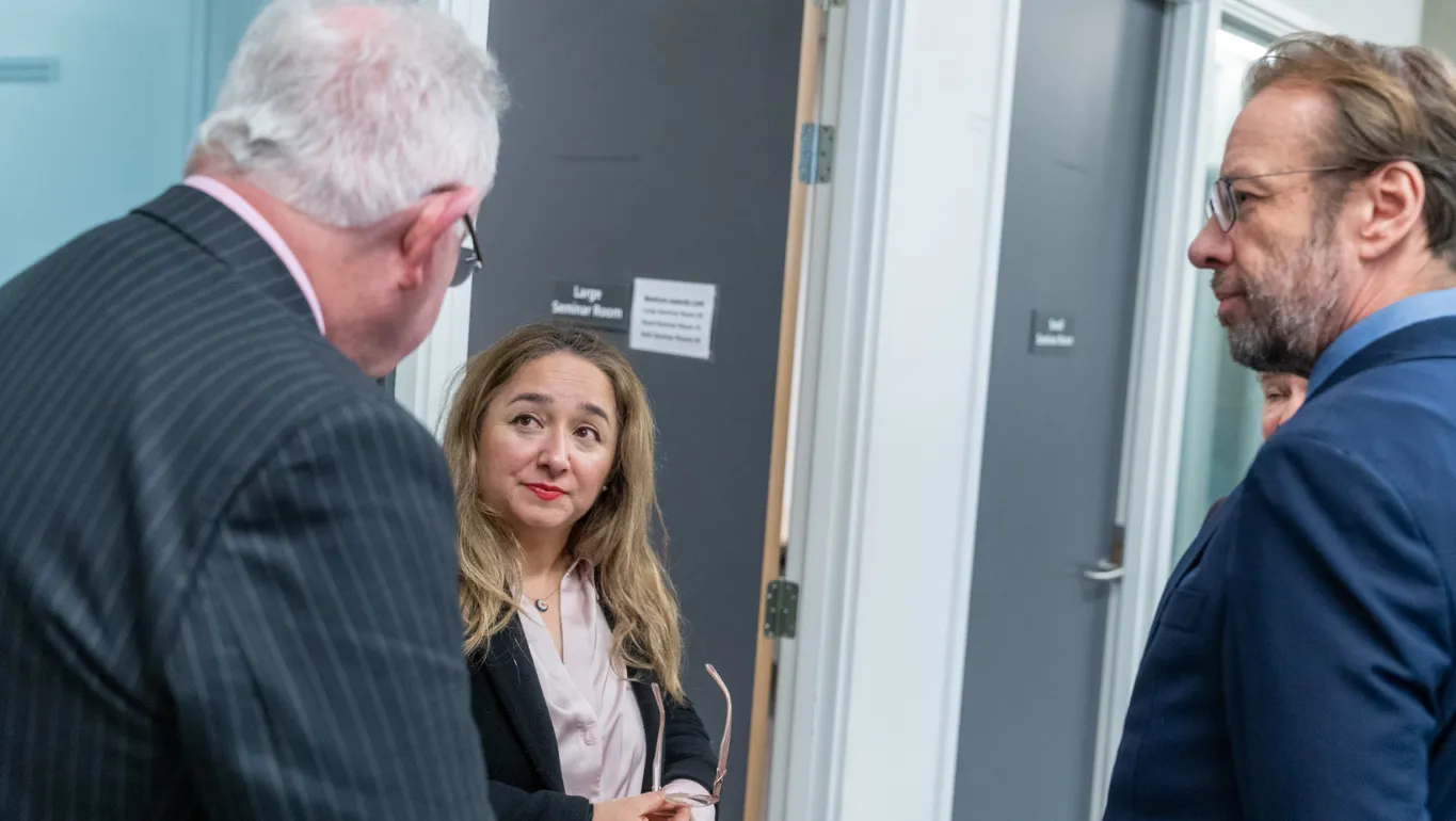 Minister Feryal Clark speaks with Professor Graham Lord (right) and Professor Sir Mark Caulfied (left)