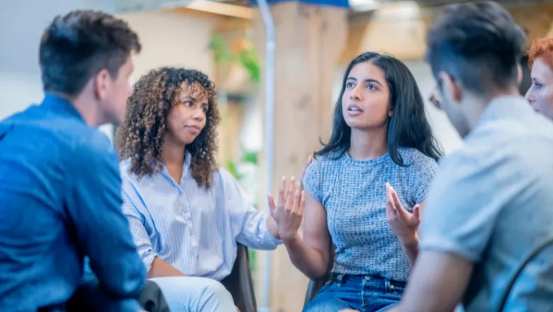 A diverse group of people sit in a circle and have a discussion