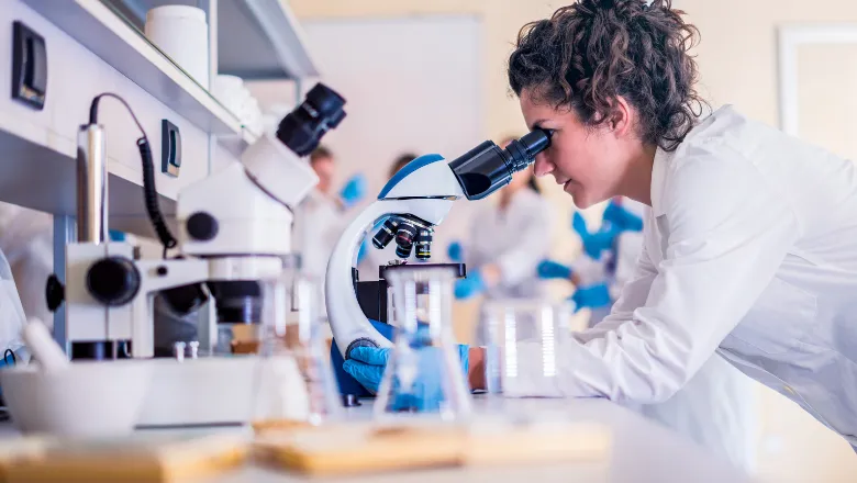 female lab technician looking into a microscope