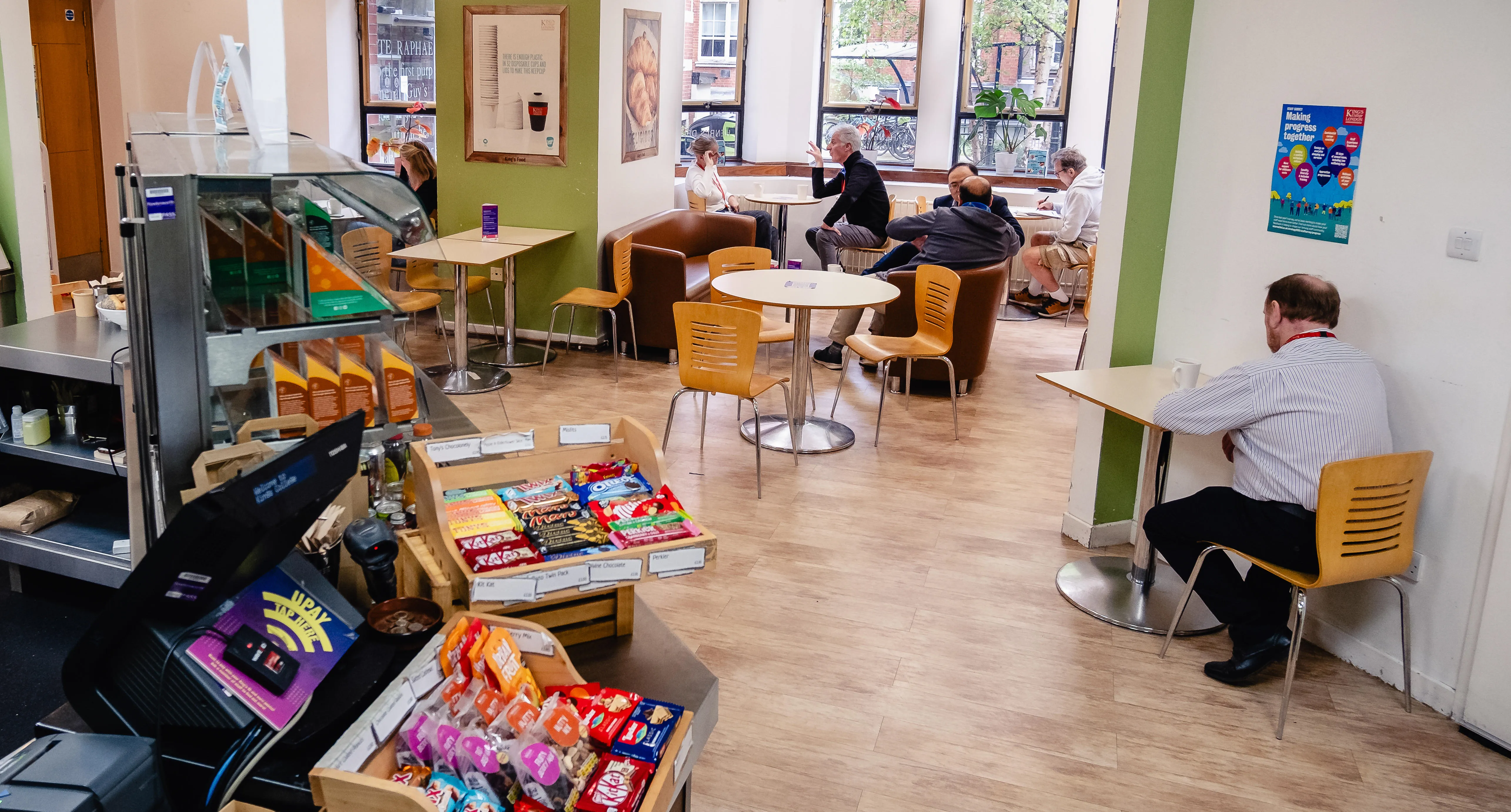 A cafe with people sitting at chairs and tables