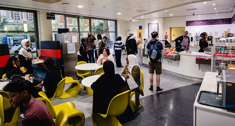 A busy cafe, with people sitting and eating at tables and chairs