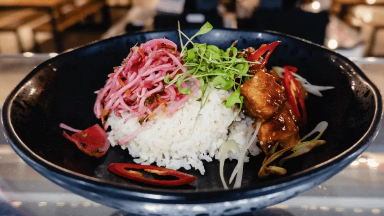 A bowl of rice topped with salad and tofu