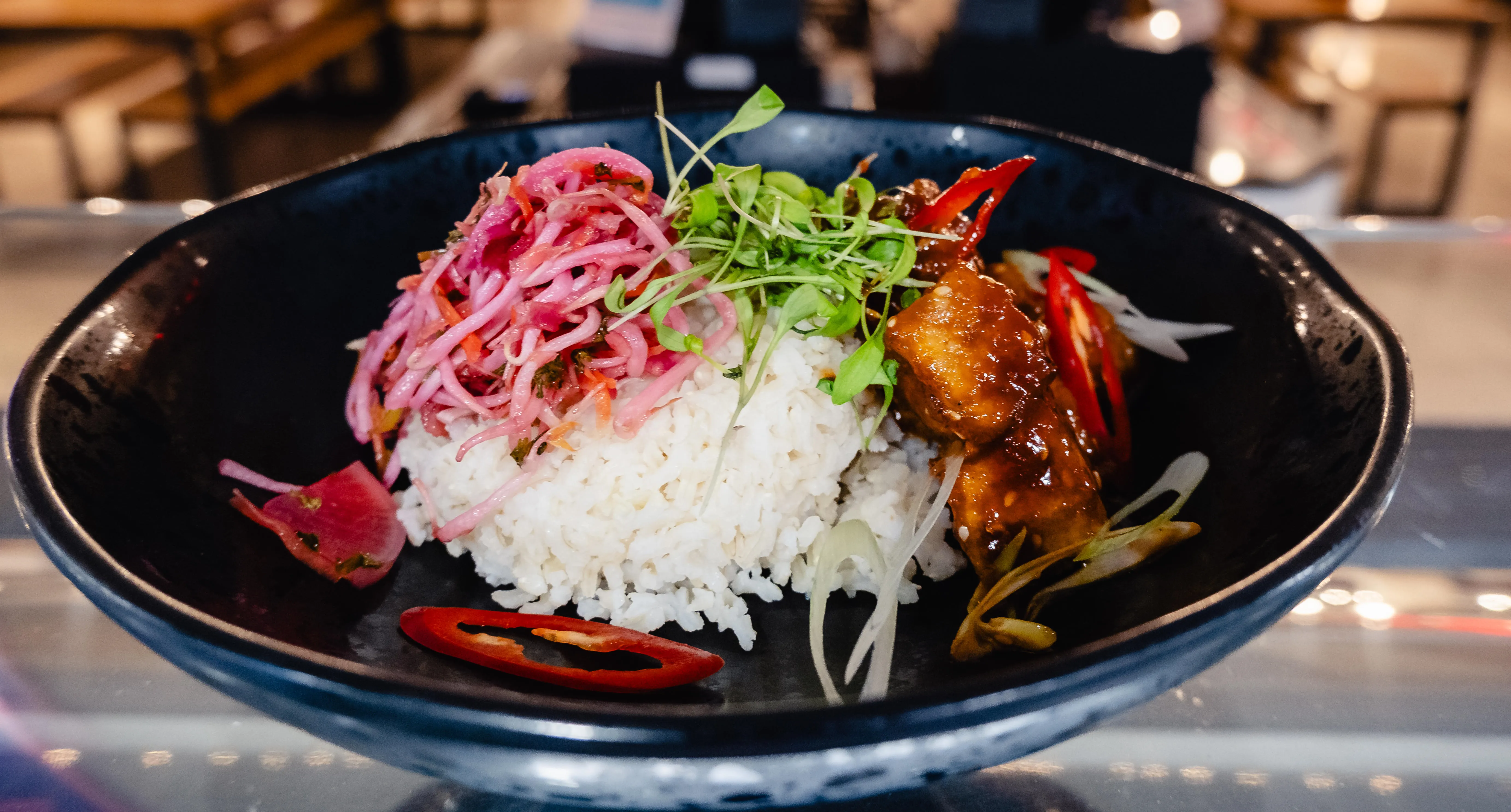 A bowl of rice topped with salad and tofu