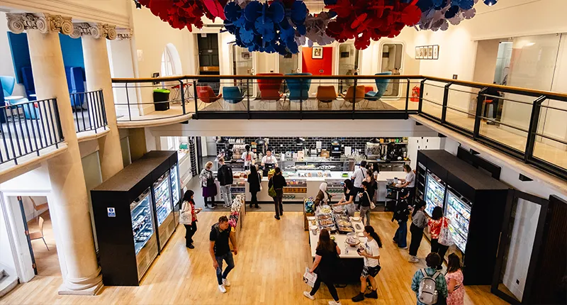 People queing to buy food, with a seating area one floor above