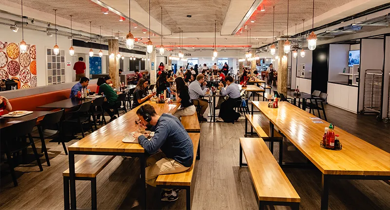 People sitting and eating at long communal tables