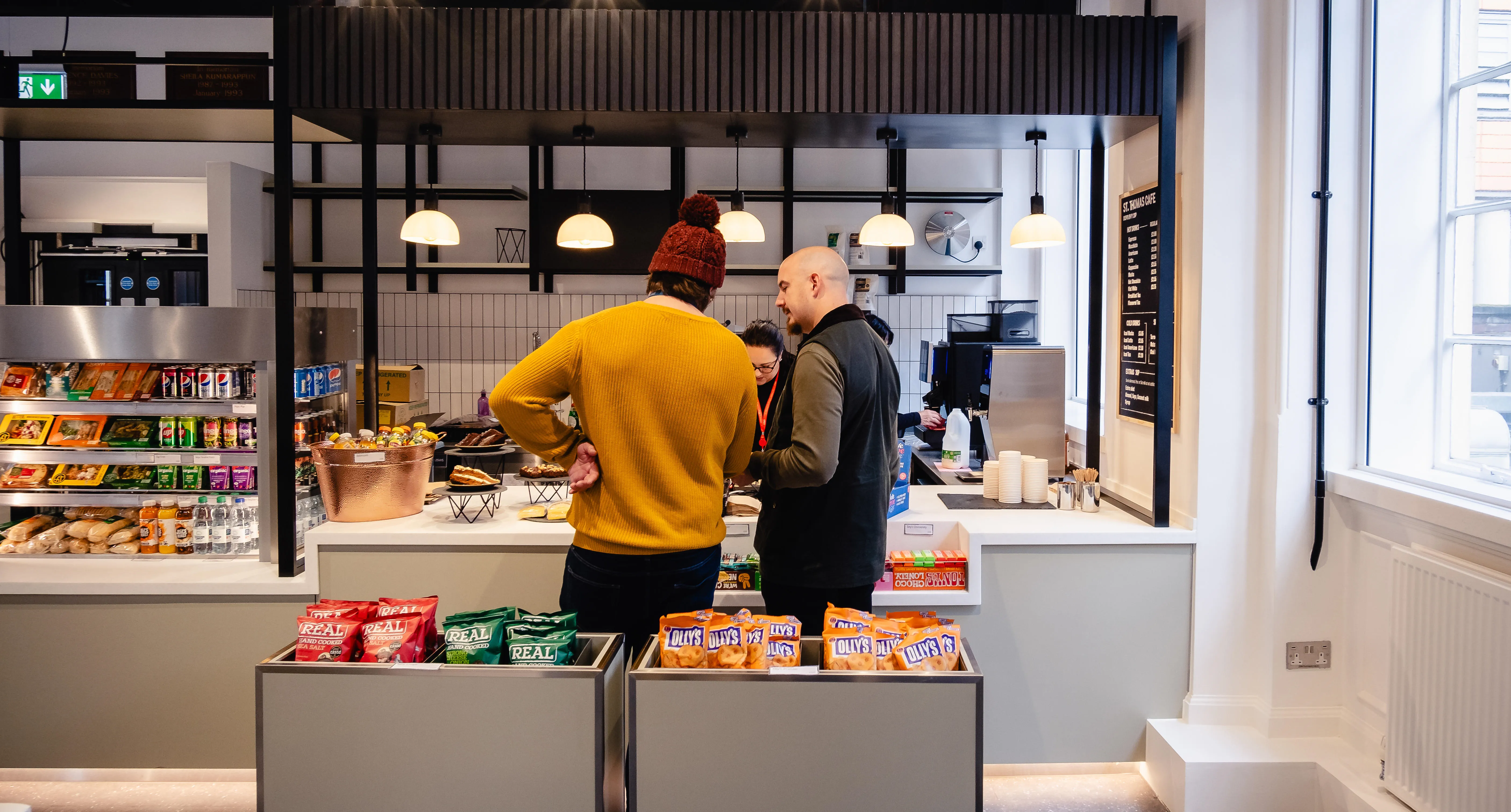 Two people queuing to pay at a cafe counter