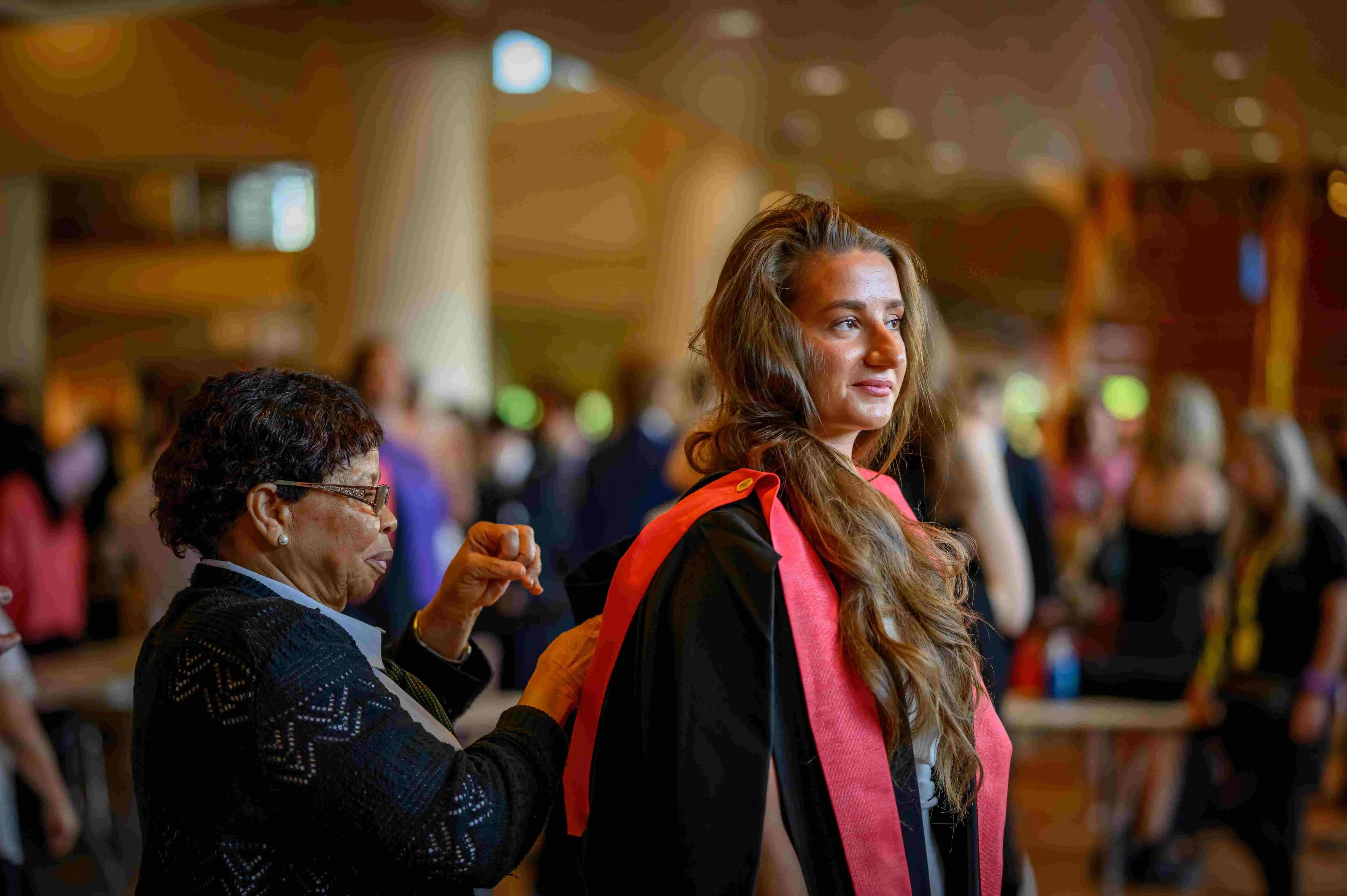 A graduate having their gown fit by a staff member prior to their ceremony in the Royal Festival Hall. 