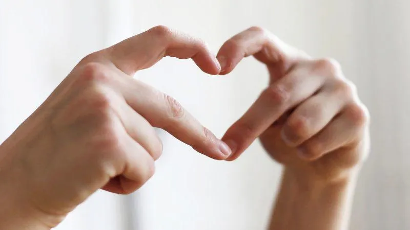 A person forms a heart shape with their hands, symbolizing love and connection.