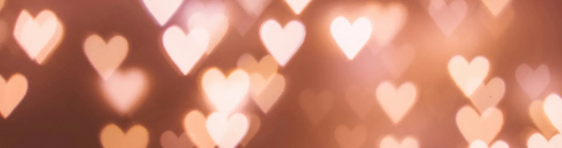 The image shows a soft, warm-toned background with multiple glowing heart shapes in a bokeh effect