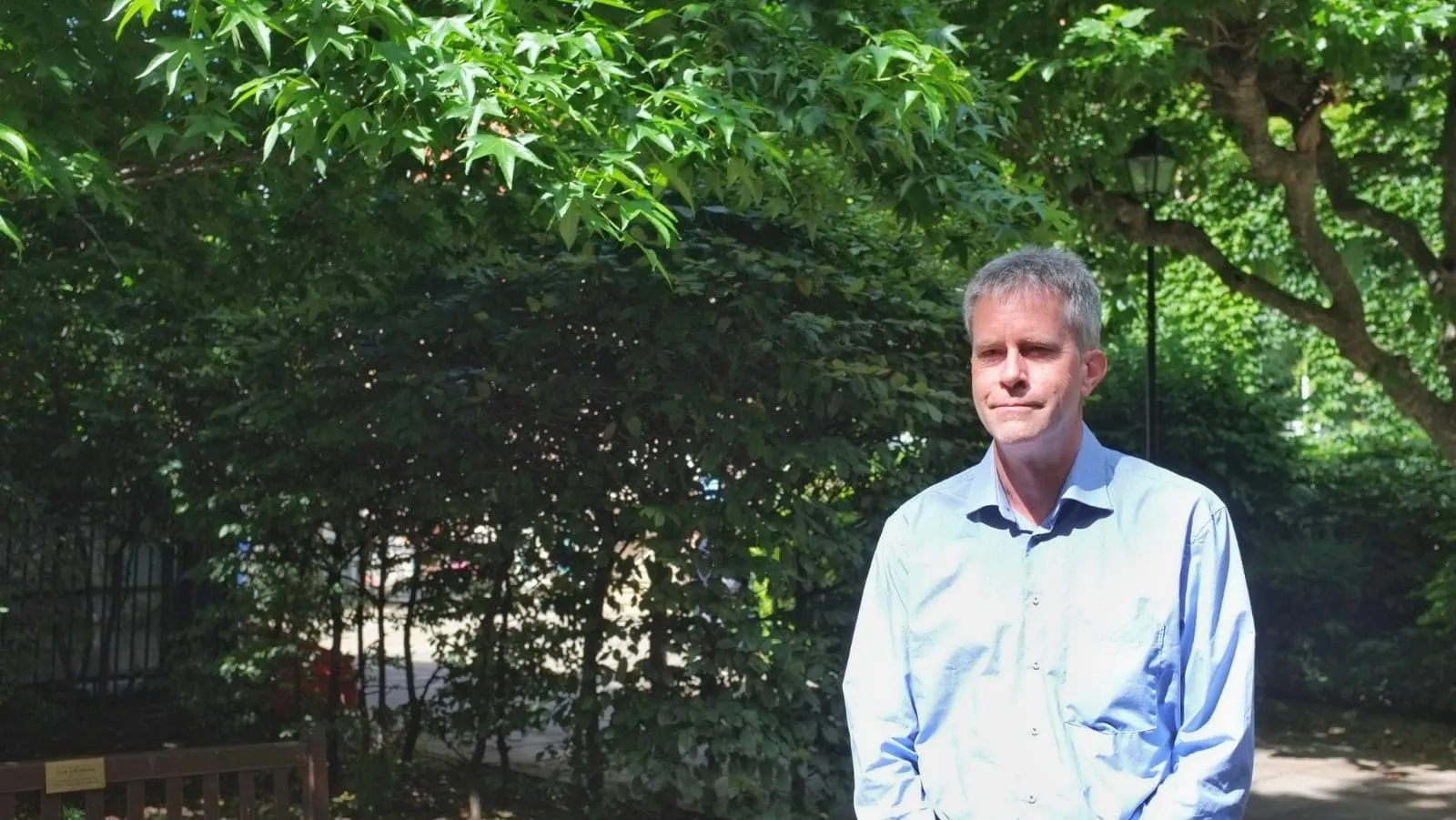Professor Ben Blencowe standing amongst the trees of the Hodgkin's building at Guy's campus