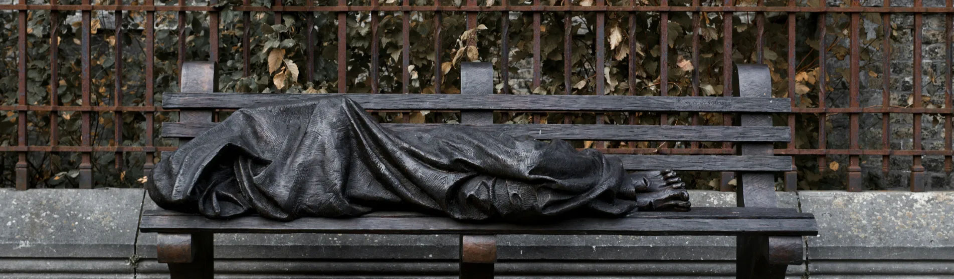 Statue of a person asleep on a bench