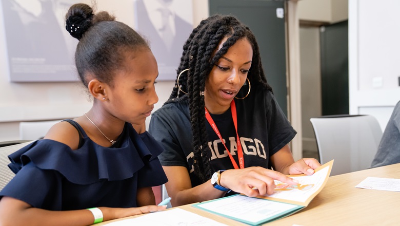 A student reading a book with a young girl