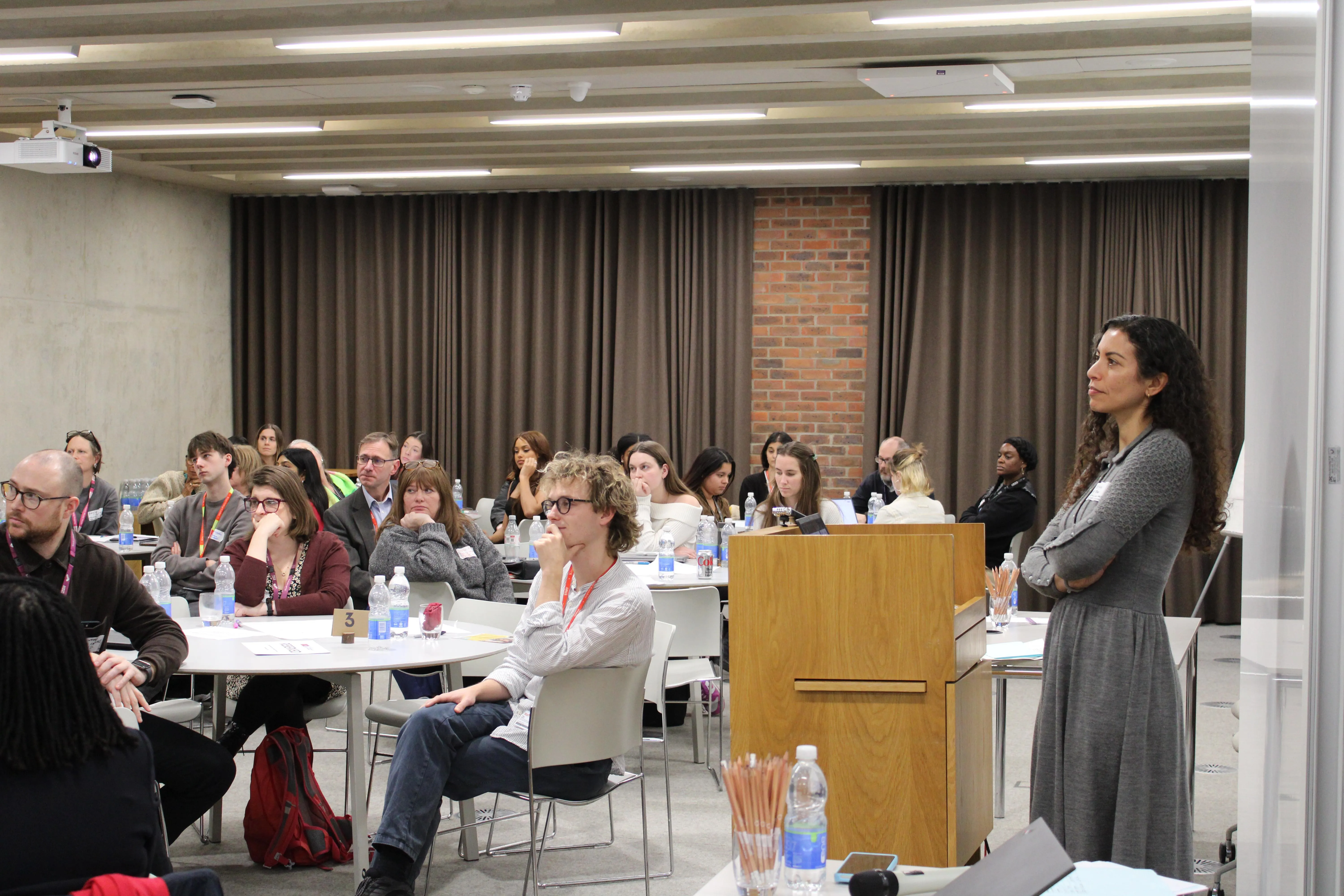 A group of people around tables listening to a presentation at the School Mental Health Innovation Network Launch