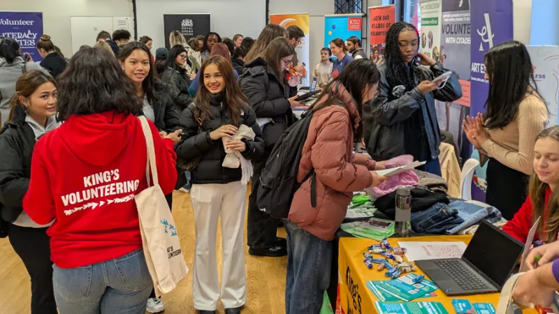 Students and staff are talking to each other at a stall during the King's Volunteering Fairs