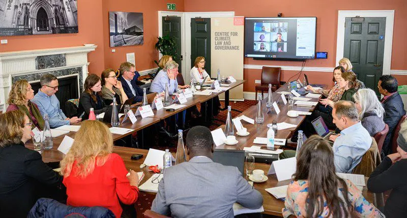 A room of people are sitting on a large table