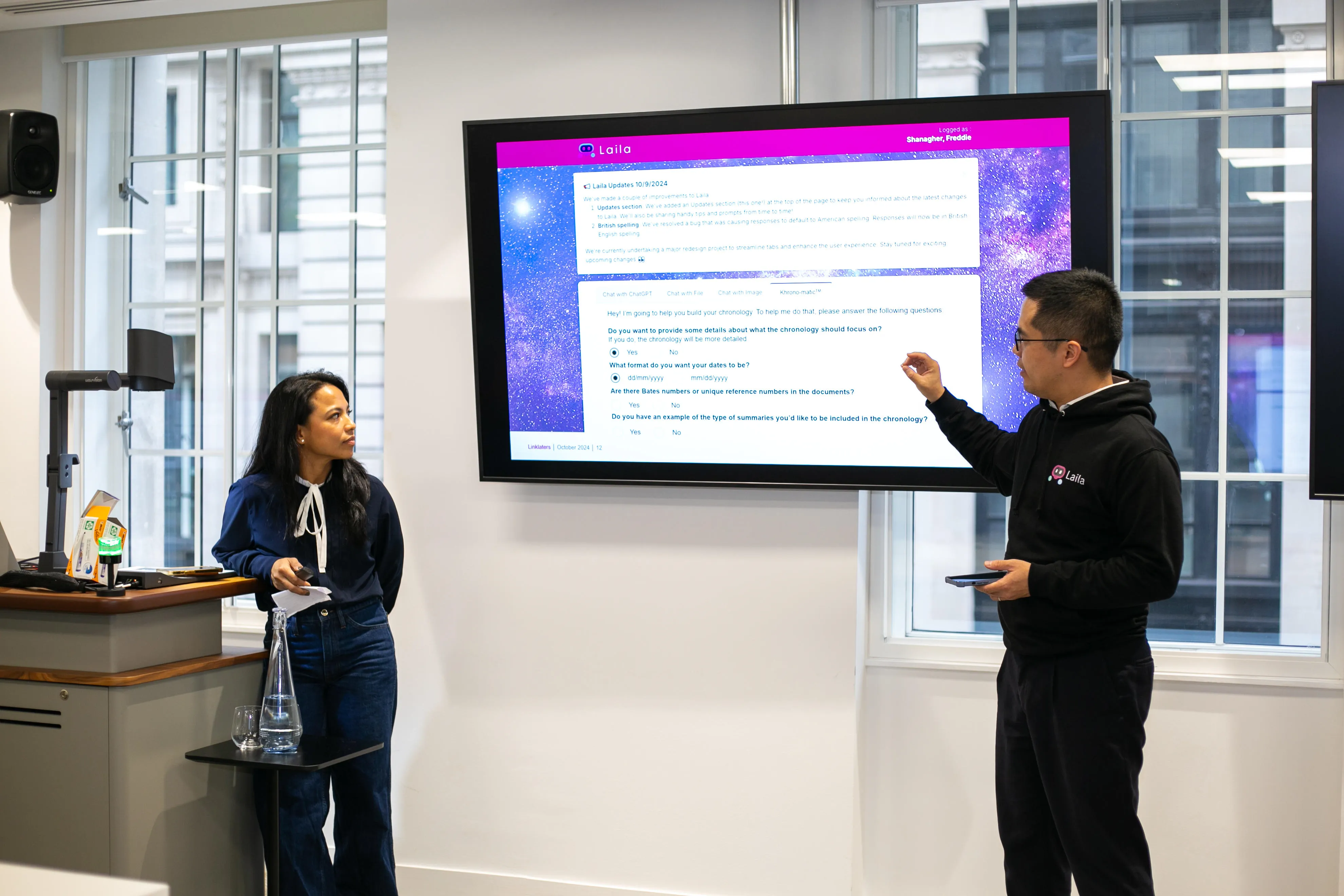 A man and a woman are in front of a screen giving a presentation